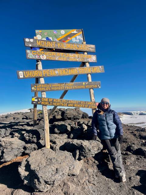 Tourist at the Uhuru Peak sign on Mount Kilimanjaro.