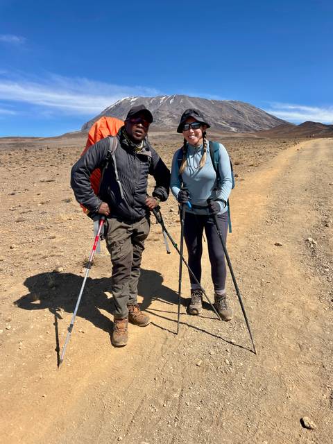 Two people with hiking gear posing on a trail.