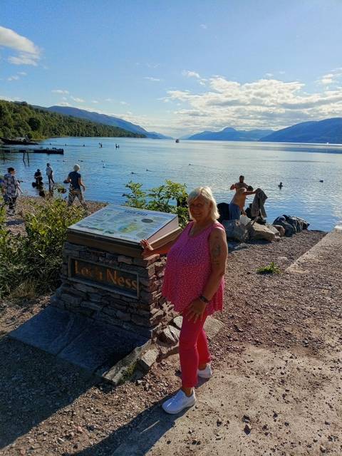 Person posing next to a sign at Loch Ness.