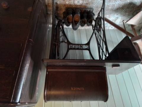 Old sewing machine with several pairs of shoes placed underneath.