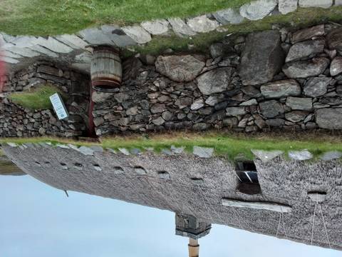 Traditional thatched roof house with stone wall.