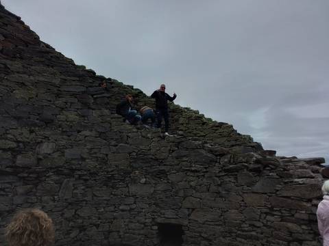 People climbing up an old stone structure.