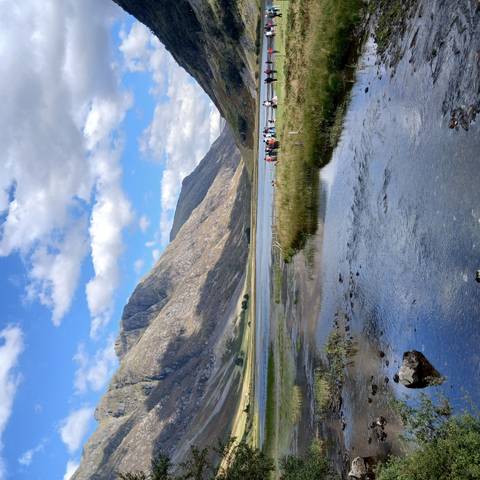 Majestic mountain landscape with a group of people by a body of water.