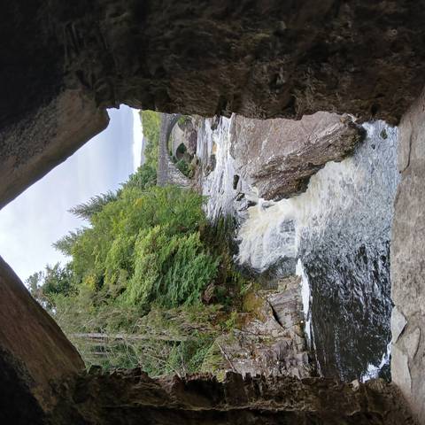 Waterfall with stone bridge in a lush forest.
