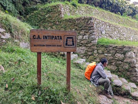 A person resting near a sign at an archaeological site.