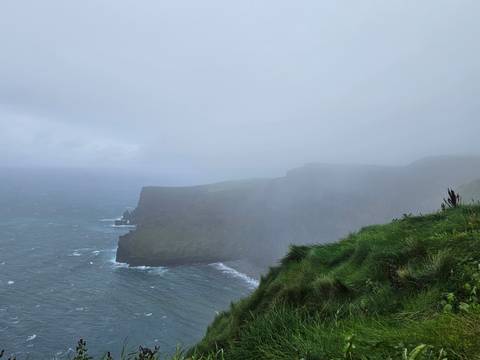 Misty cliffs overlooking a rough sea.