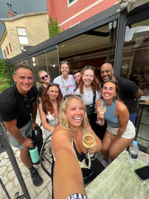 Group of people smiling and holding drinks in a restaurant setting.