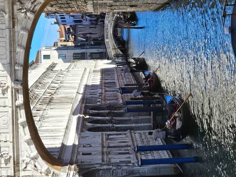 Venetian gondoliers rowing through a canal.