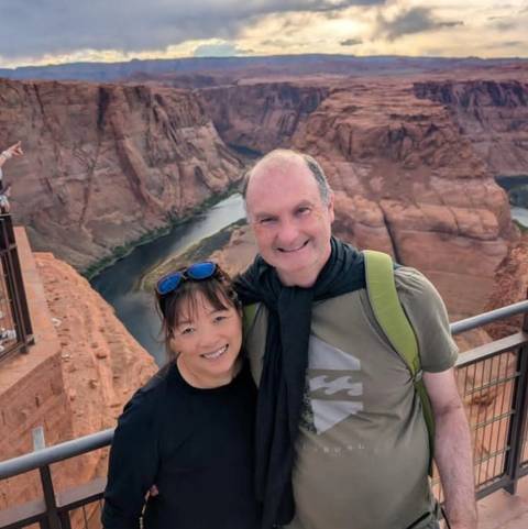 A couple smiling with a scenic canyon view behind them.