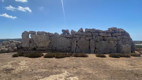 Ancient stone structure ruins under a clear sky.