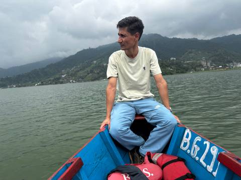 A man sitting in a boat on a lake surrounded by hills