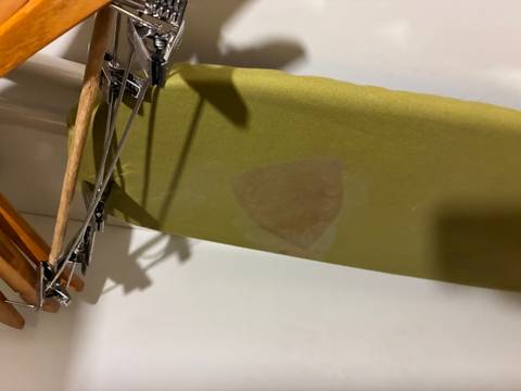 Ironing board with a stained cover.