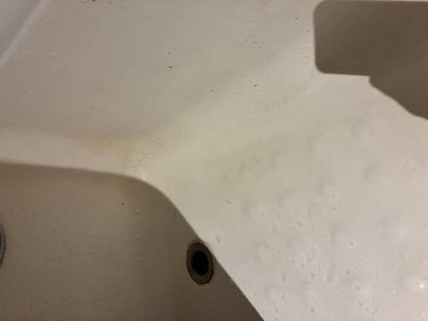 White sink with water spots and drain.