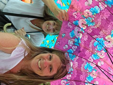 Two women under floral umbrellas.