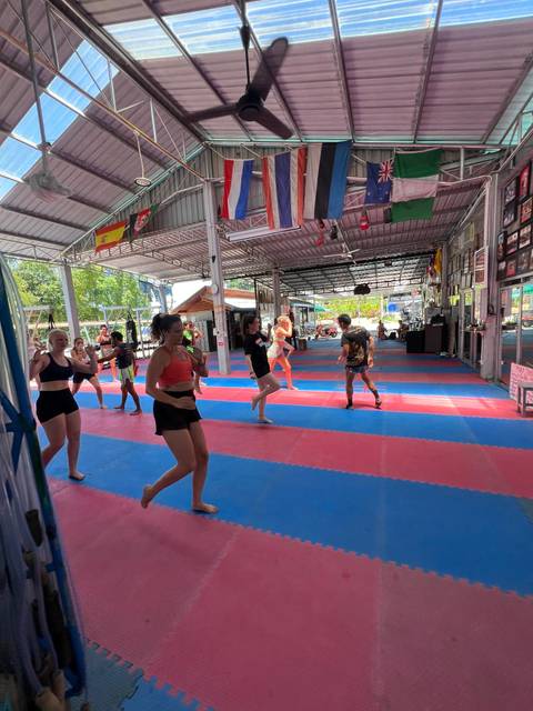 People exercising in a gym with flags and mats.
