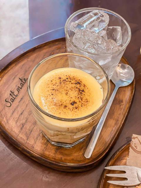 Glass of creamy beverage with spoon on a tray.