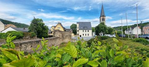 A small village with a church tower and green foliage.