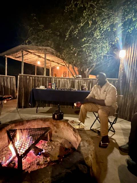 Person sitting by a campfire in a rustic setting at night.