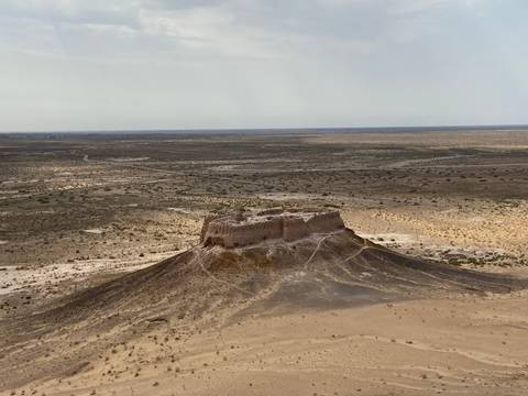 Ruined fortress atop a hill in a barren landscape.