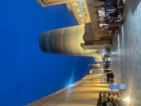 Night view of tall, blue-tiled tower and street in an ancient city.