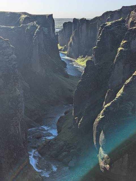 River gorge with steep rocky walls and sunlight filtering through.