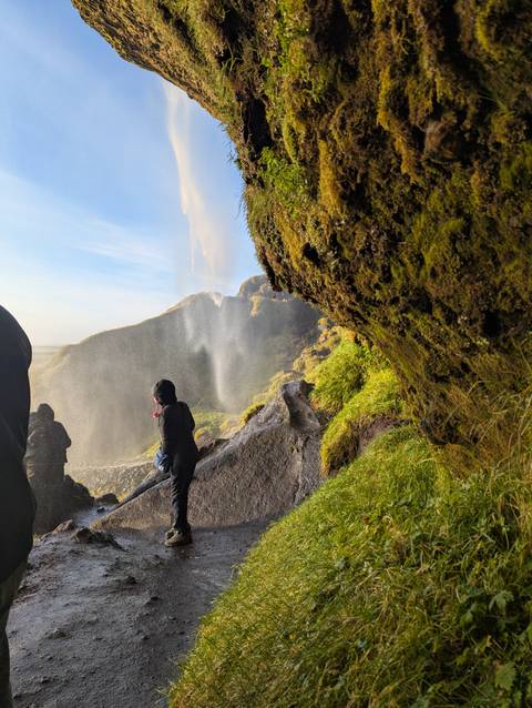 People sitting on rocks near a large waterfall.