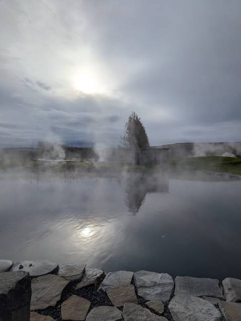 Steaming geothermal pool in a misty landscape.