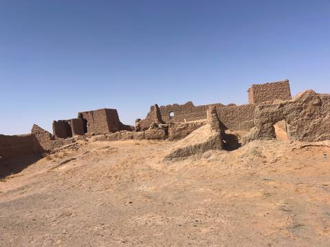 Ruins of ancient structures in a sandy area.