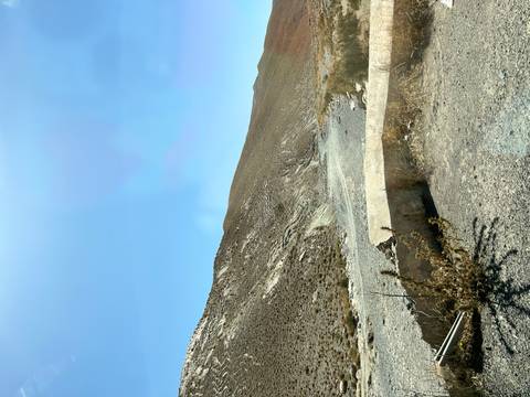 Rocky landscape with barren hills under clear blue sky.