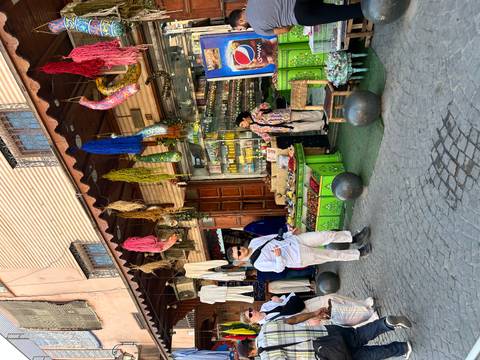 Market scene with people and colorful items on display.