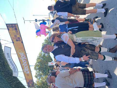 Couple posing under an Oktoberfest welcome sign.