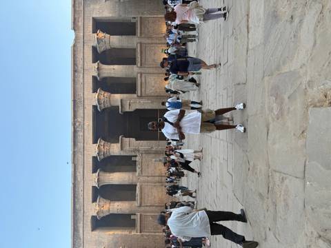 Man standing in front of an ancient Egyptian temple with a group of tourists.