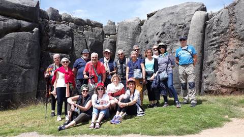 Group of tourists posing in front of ancient stone ruins