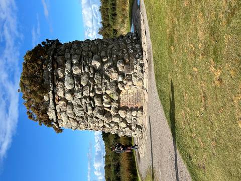 A memorial cairn on a sunny day with blue sky.