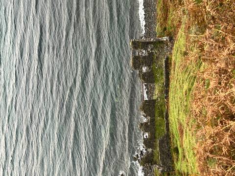 A shoreline view with remnants of stone walls.