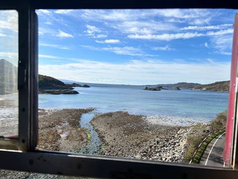 A scenic coastal view from a window with distant islands.
