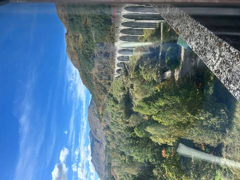 A view of a viaduct surrounded by greenery and mountains.