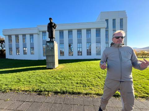 Person wearing a jacket standing in front of a statue.