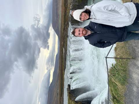 Couple standing with a scenic waterfall in the background.