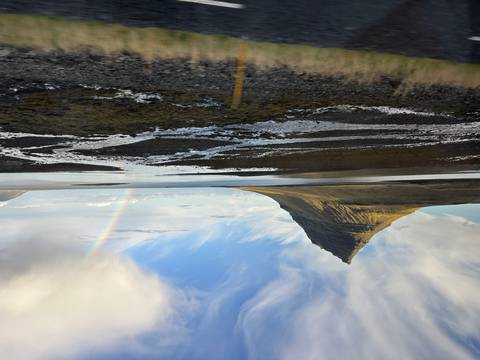A scenic view of Kirkjufell Mountain with a rainbow in the background.