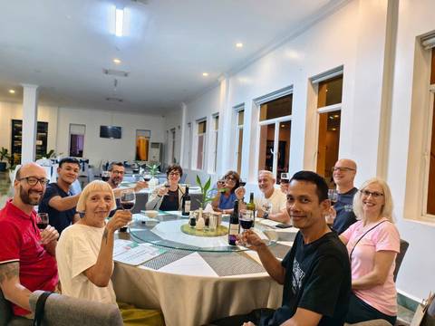 Group of people sitting around a table, raising glasses.