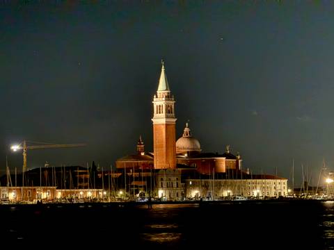 Night view of a lit church with tall spire in Venice.
