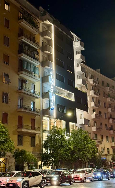 Street view of a lit modern building at night.