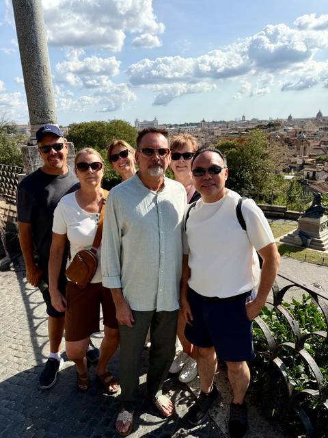 Group of six people posing in front of a cityscape.