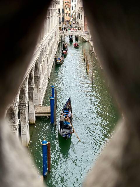 A gondola with people on a Venetian canal.