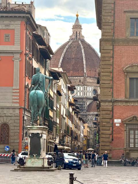 Statue of a horse and rider in front of the Florence Cathedral dome.