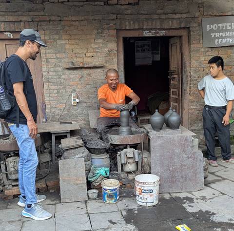 Potter at work shaping a pot on a pottery wheel.