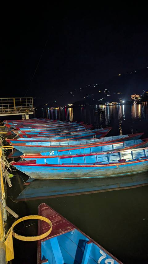 Colorful boats lined up at night with reflections on the water.
