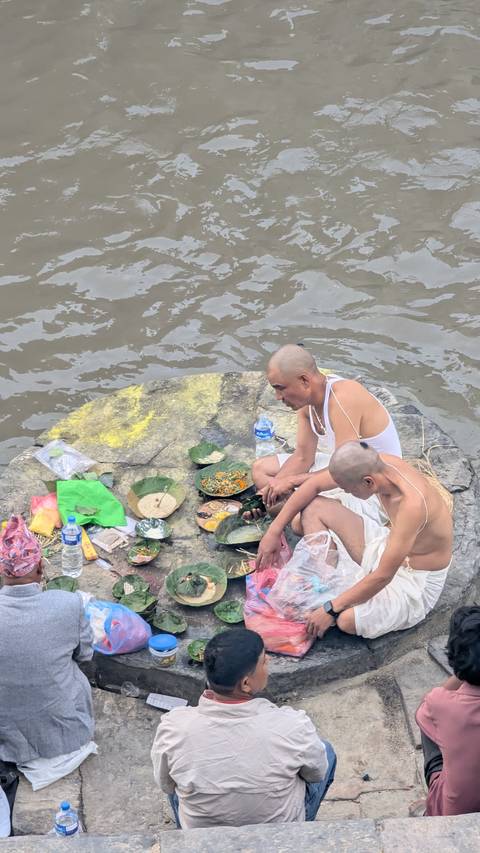 Two people sitting by a river having a meal.