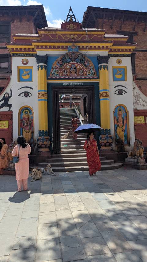 Temple entrance with intricate carvings and people standing.